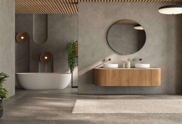 Salle de bains moderne naturelle avec meuble double vasque suspendu en bois, miroir rond, baignoire îlot et murs effet béton.